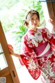 A woman in a red and white kimono leaning against a door.