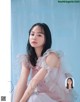 A woman in a pink dress sitting on a blue background.