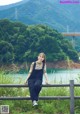 A woman sitting on a fence in front of a river.