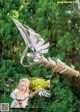 A picture of a woman holding a sword in front of a forest.