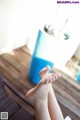 A woman's bare feet on a wooden floor next to a blue bucket.