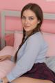 A young woman sitting on top of a bed.