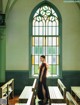 A woman standing in front of a stained glass window.