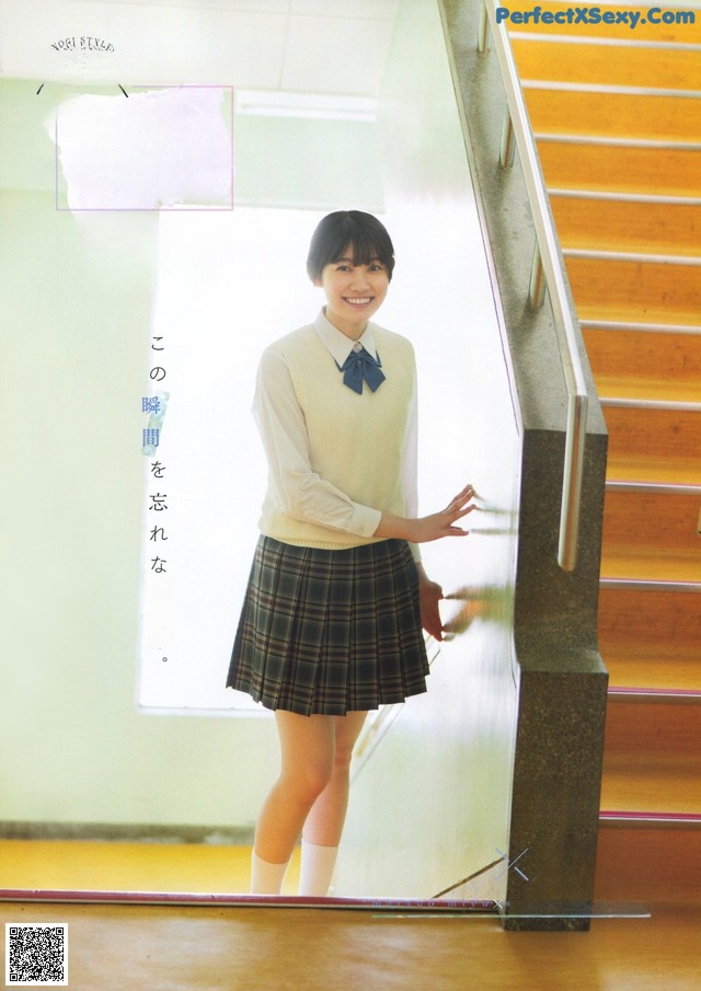 A woman in a school uniform standing in front of a staircase.
