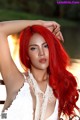 A woman with long red hair wearing a white dress.