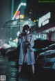 A woman in a white coat holding an umbrella in the rain.