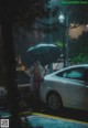 A naked woman standing in the rain holding an umbrella.